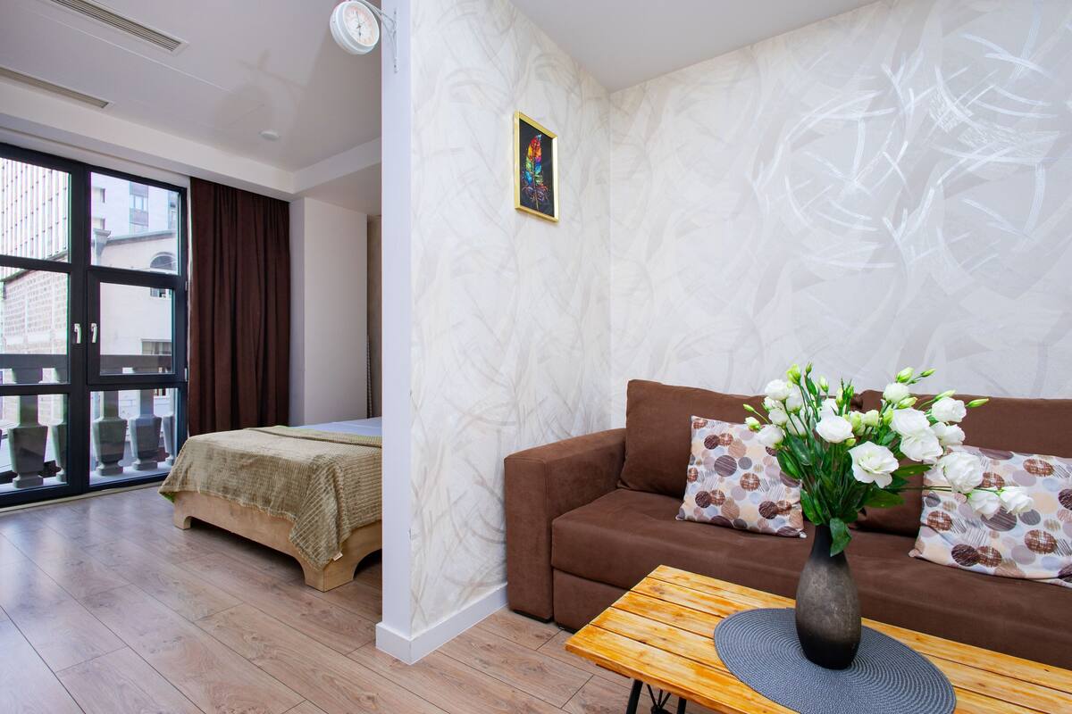 Ein modernes Wohnzimmer mit einer Couch, einem Couchtisch und einer Blumenvase.