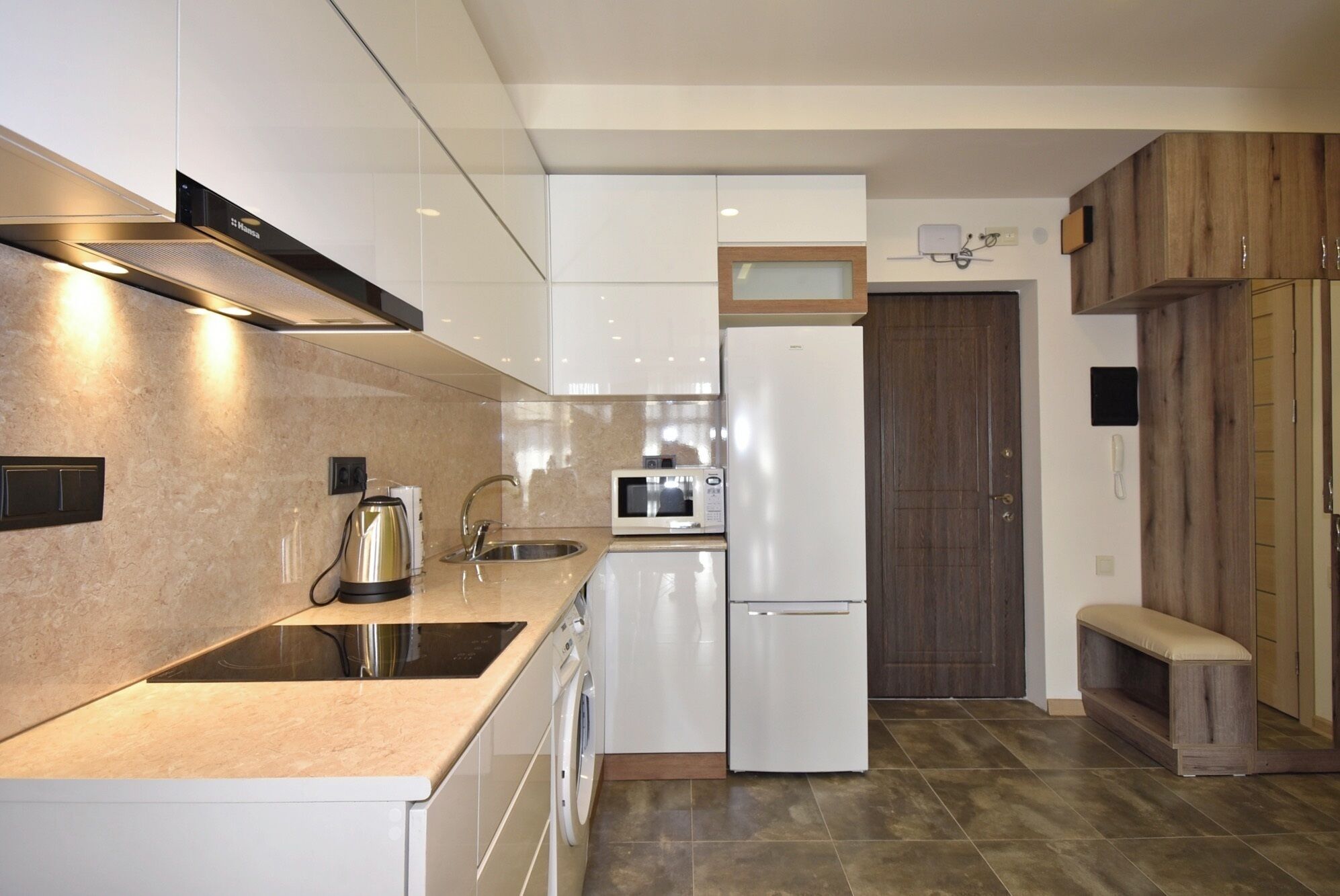 Una cocina moderna con microondas integrado, hervidor y pileta.