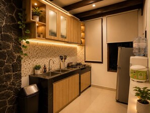 A modern kitchen with a stone accent wall, wooden cabinets, and a black countertop.