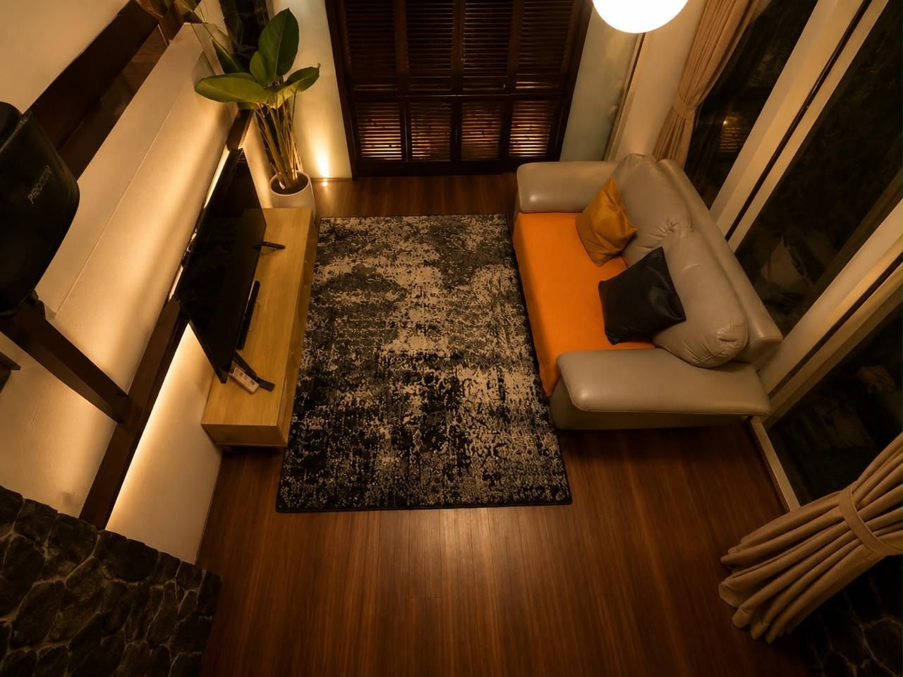 Ein modernes Wohnzimmer mit einer Couch, einem Fernseher, einem Couchtisch aus Holz und einem gemusterten Teppich.