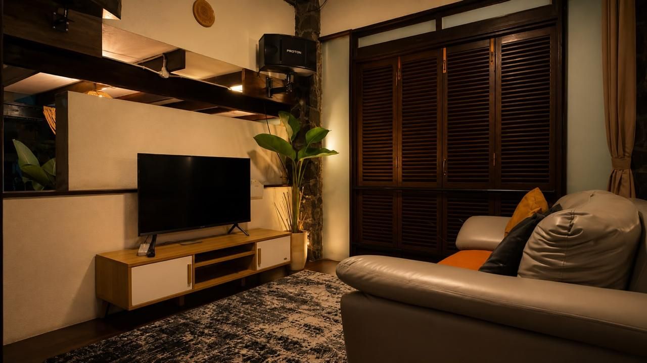 Ein modernes Wohnzimmer mit einem Flachbildfernseher, einer Holz-Unterhaltungsecke, einer Topfpflanze und einem Ledersofa.