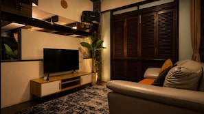 Una sala de estar moderna con un televisor de pantalla plana, mueble de entretenimiento de madera, una planta en maceta y un sofá de cuero.