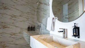 Een moderne badkamer met een marmeren achterwand, een grote spiegel, een rechthoekig wastafelmeubel en een handdouche.