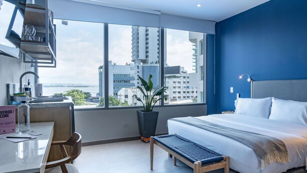 Een moderne hotelkamer met een groot bed, een bureau en uitzicht op de stad.