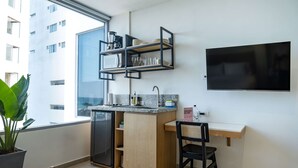 A modern kitchen with a built-in refrigerator, wooden cabinets, a black chair, and a flat-screen TV mounted on the wall.