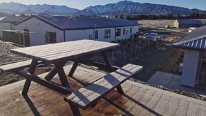 Eine Holzterrasse mit Picknicktisch, mit Blick auf eine Wohngegend, mit Häusern und Bergen im Hintergrund.