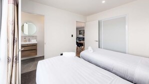 Ein Hotelzimmer mit Bett, Badezimmer inklusive Spiegel und Schreibtisch mit Stuhl.