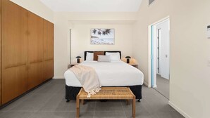 Ein Schlafzimmer mit einem Bett, Nachttischen, einem Holzschrank, einer Bank und einem an der Wand hängenden Bild.