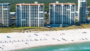 Un hotel frente a la playa con varios edificios altos, una playa de arena y una zona de piscina.