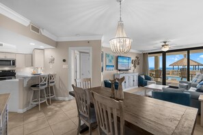 A modern kitchen with a dining area, a TV, and a view of the ocean. - Beachfront 3 Bed Ground Floor at Summer House in OB! Free Daily Activities! (Orange Beach)