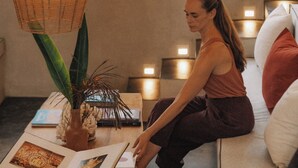 A woman sitting on a sofa with a laptop, surrounded by books and a decorative plant. - D' Art Villa Retreat and Spa (Tangalle)