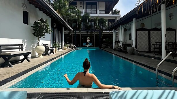 A swimming pool with a person in the water, surrounded by lounge chairs and potted plants. - D' Art Villa Retreat and Spa (Tangalle)
