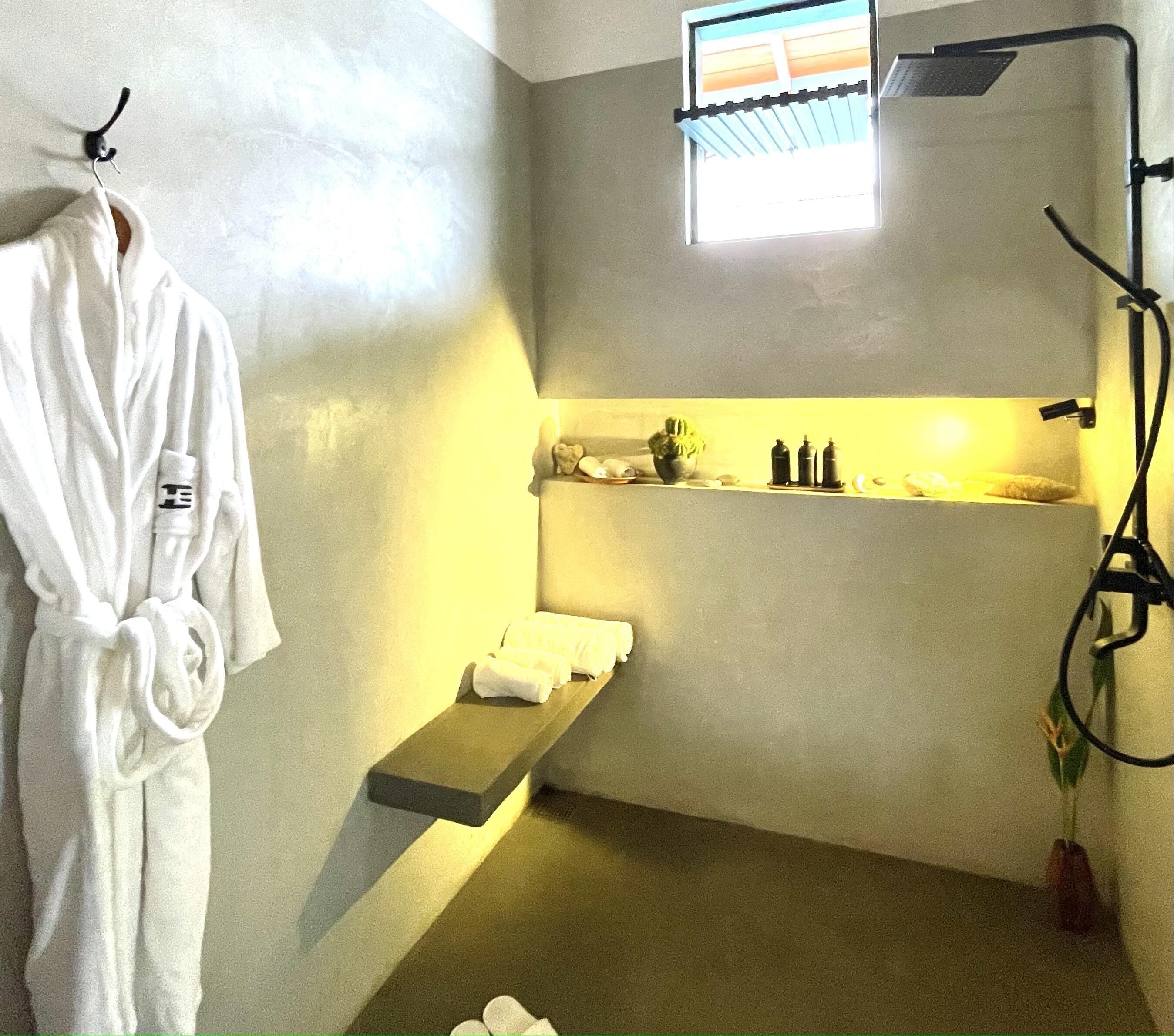 A bathroom with a towel rack, a shelf with toiletries, and a shower area.