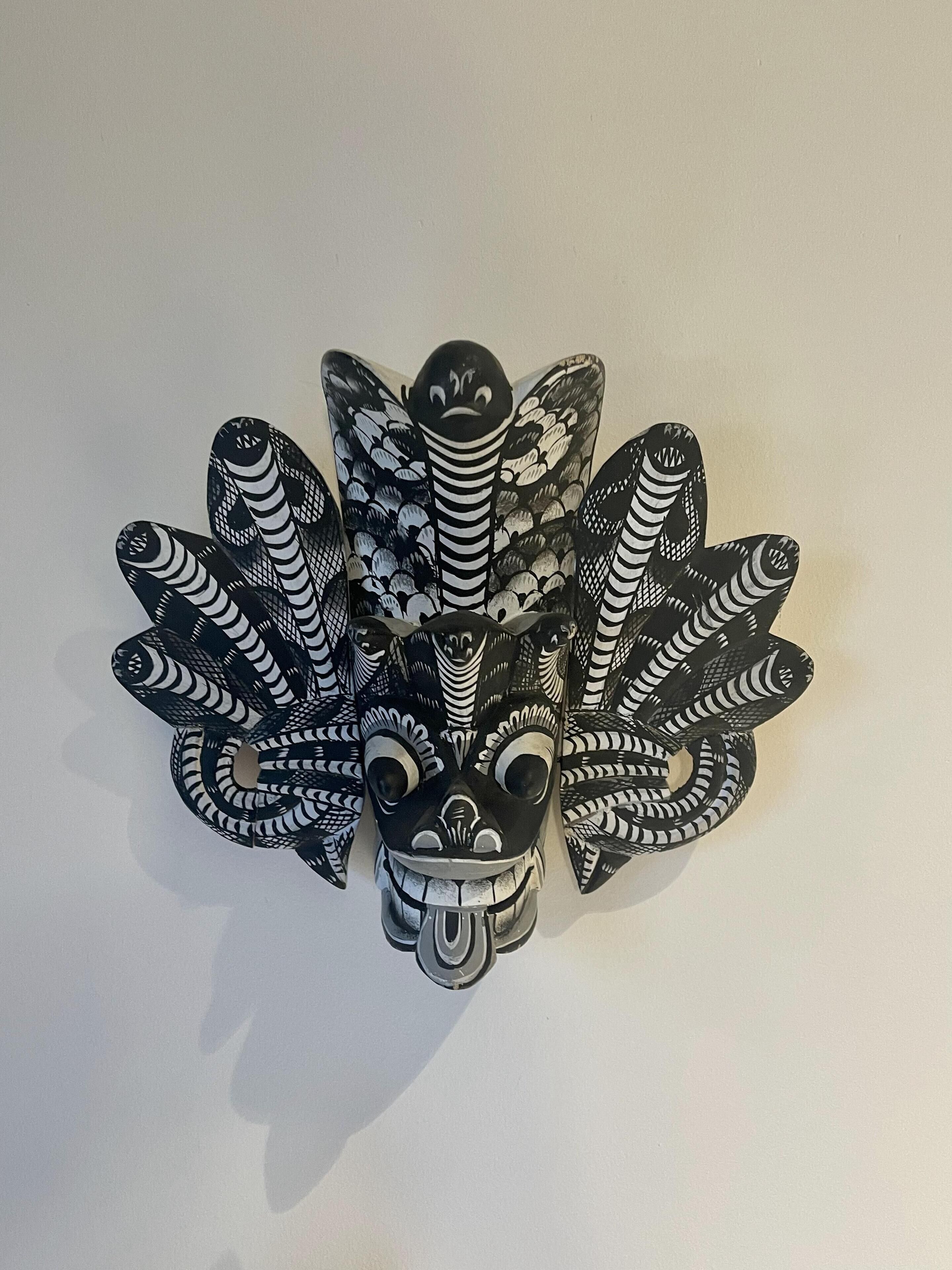 Un objeto decorativo en blanco y negro con múltiples elementos serpentinos y un rostro central.