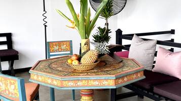 A dining area with a round table, chairs, a wall-mounted fan, and a decorative wall piece.