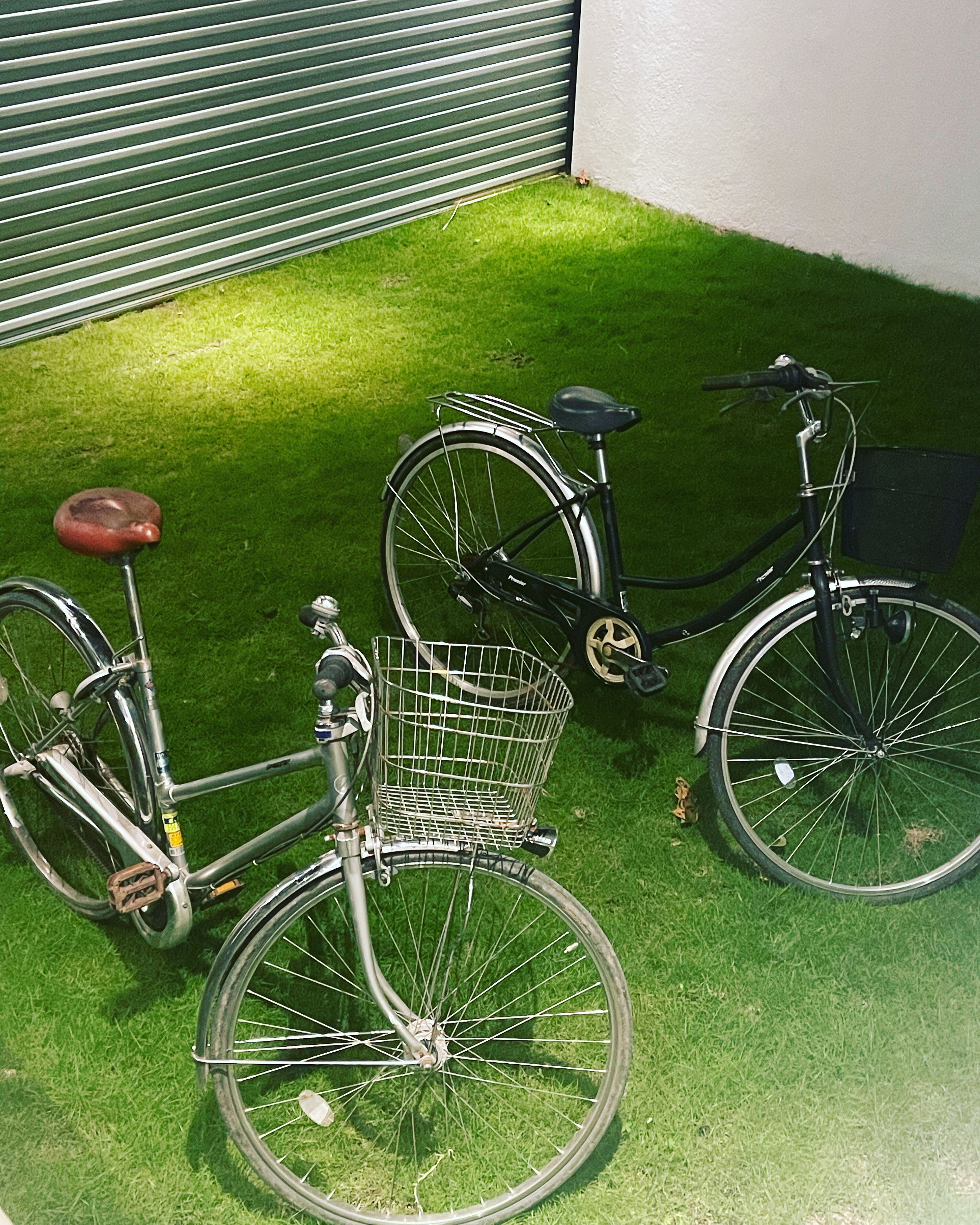 A bicycle with a basket and a seat, parked on artificial grass.