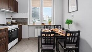 A modern kitchen with a dining area, featuring a stove, oven, and dining table with chairs. - City center Apart near Palace of Culture (Warsaw)