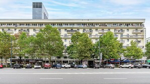 A multi-story building with balconies, parked cars, and trees in front. - City center Apart near Palace of Culture (Warsaw)