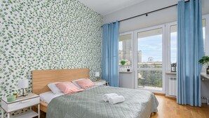 A bedroom with a bed, nightstands, a window with curtains, and a city view. - City center Apart near Palace of Culture (Warsaw)