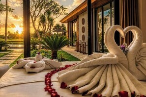 Un cadre luxueux agrémenté d’une décoration originale en forme de cygne réalisée avec des serviettes, offrant une vue sur le jardin et donnant accès à une piscine.