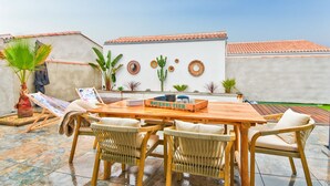 Une terrasse extérieure avec une table en bois, des chaises en osier et une enseigne indiquant « NOIR MOUTIER ».