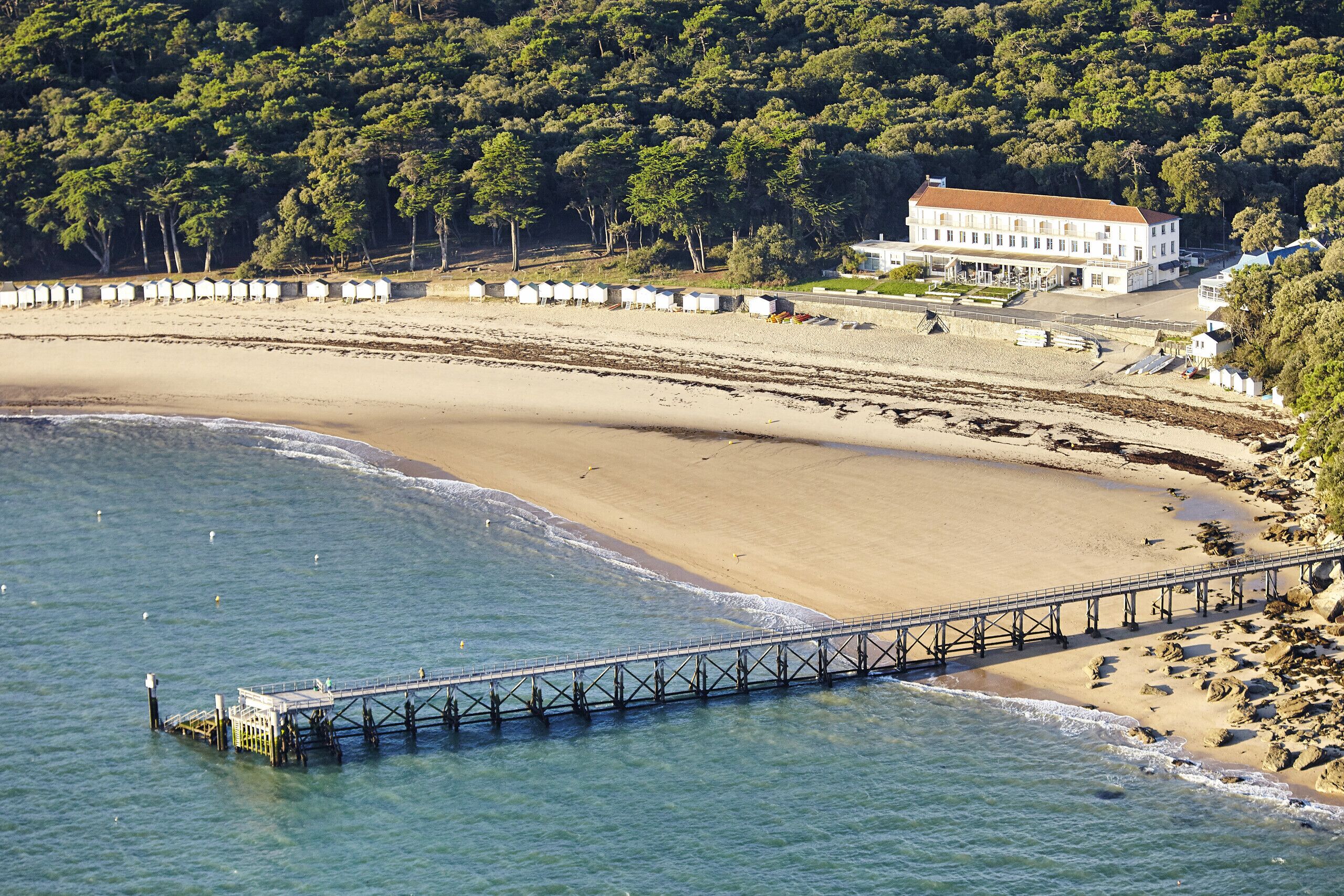 Een kustgezicht met een strand, een pier en een gebouw.