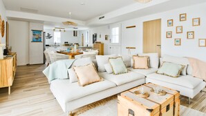 Un salon moderne avec un canapé blanc, une table basse en bois et un coin repas comprenant une table et des chaises.
