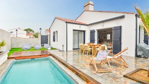 Une maison moderne dotée d’une piscine, d’un espace salon extérieur et d’un patio.