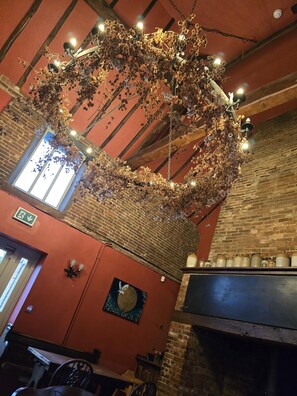 L’intérieur d’un restaurant avec des murs en briques, une composition florale suspendue, une fresque murale et un four en briques.