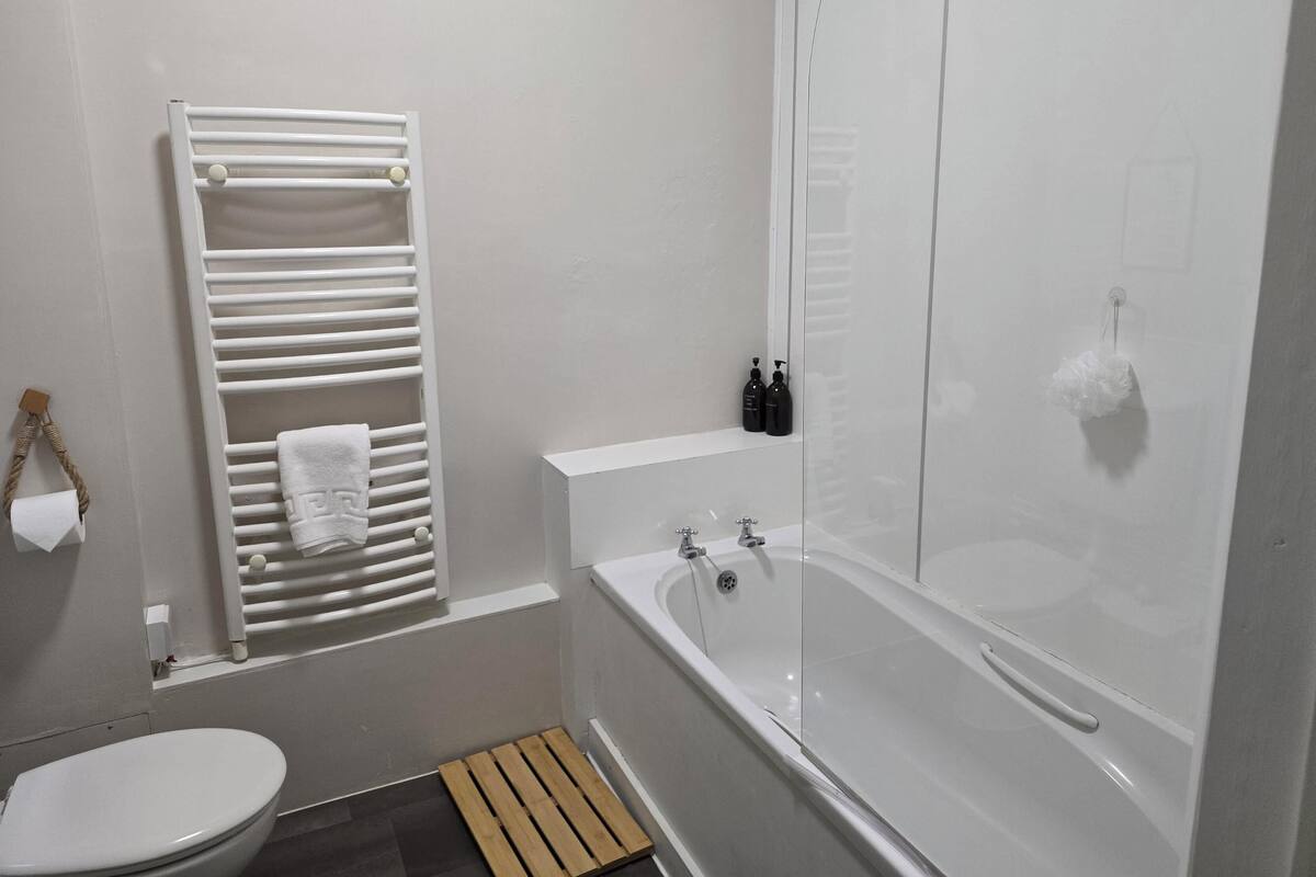 Un bagno con il water, un portasciugamani, una doccia e una vasca.