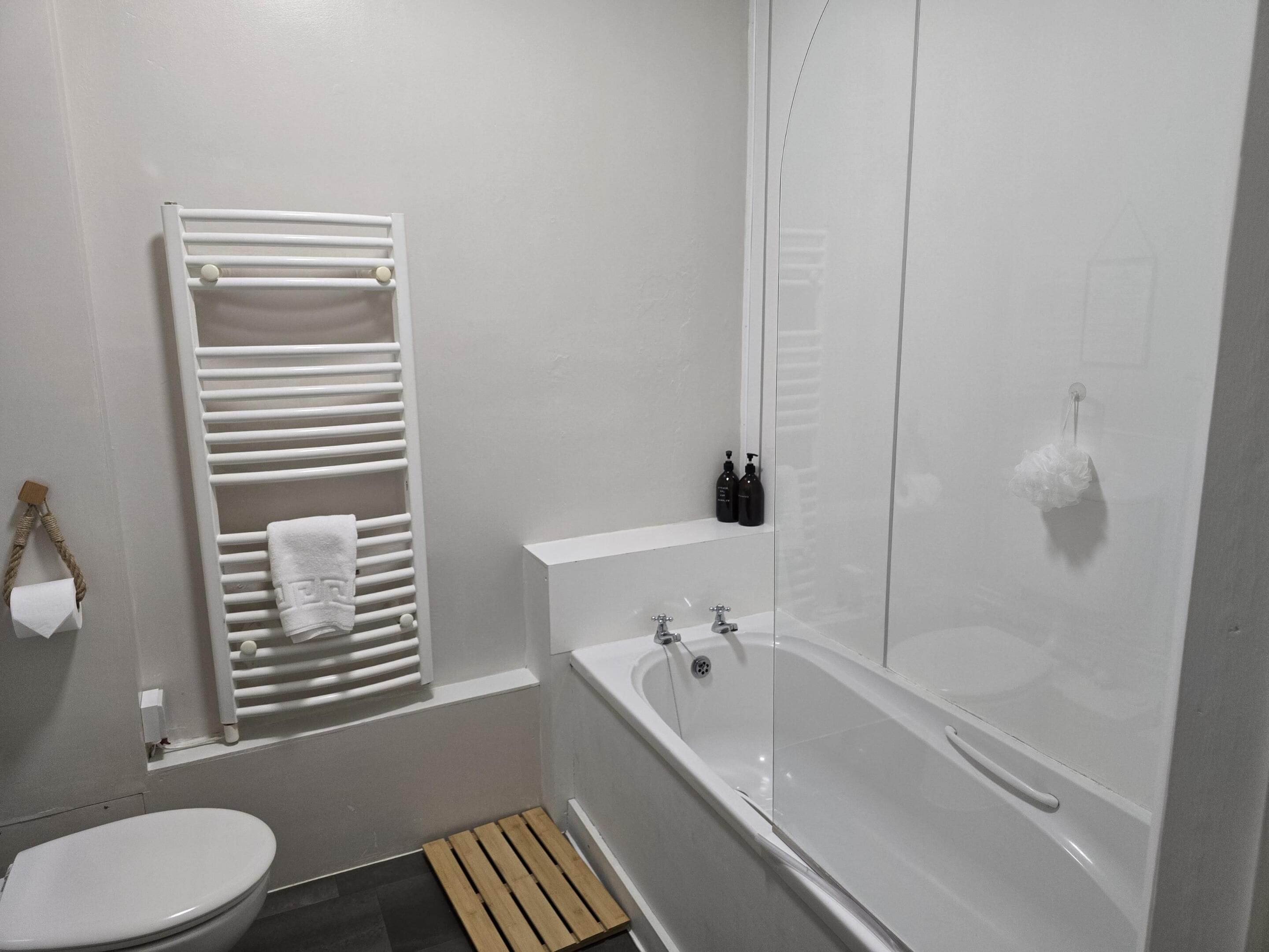 Un baño con inodoro, toallero, bañera y zona de ducha.