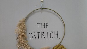 A wall-mounted decorative wreath with the text "THE OSTRICH." - The Ostrich (Castle Acre)