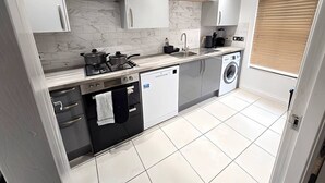 Cozinha moderna com armários brancos, lava-louças, máquina de lavar e fogão.