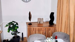 Una sala de estar moderna con una mesa de centro de madera, una planta en maceta, un reloj de pared y una escultura abstracta negra.