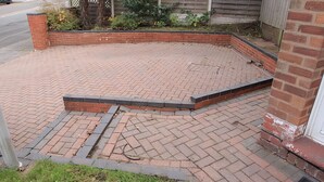 Un patio empedrado con suelo de ladrillo y un muro bajo de ladrillo.