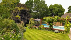 A well-maintained garden with a swimming pool, surrounded by lush greenery and various plants.