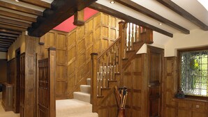 A wooden staircase with a beige carpet, wooden doors, and a stained glass window.