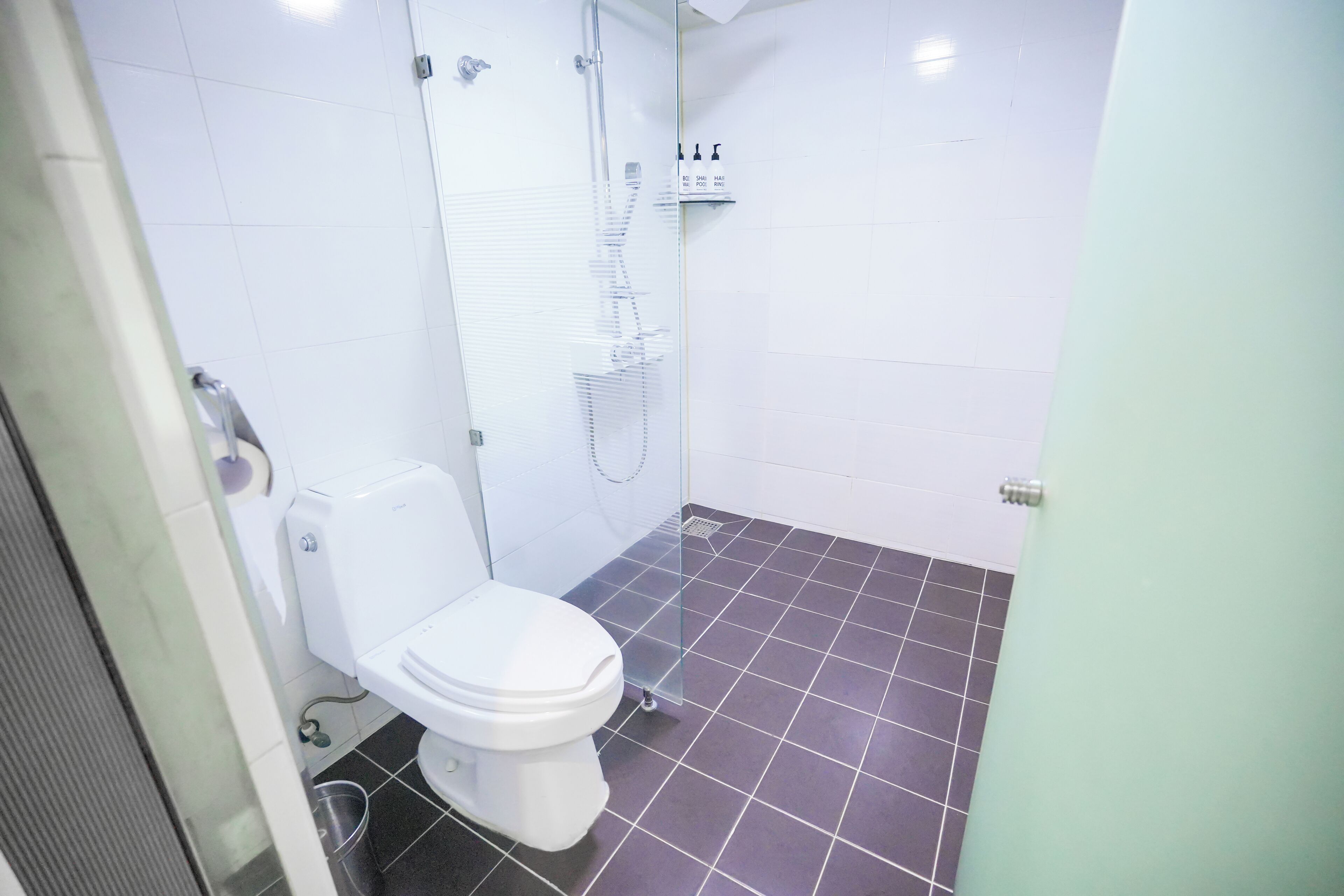 A bathroom with a toilet, a shower, and a tiled floor.