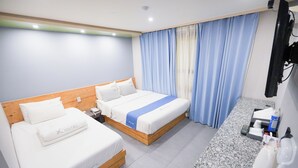 Habitación de hotel con dos camas, cabecero de madera, encimera de mármol, lavabo y espejo.