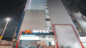 Un edificio con un letrero que dice 'Motel' y un letrero que dice 'MU Fitness', indicando instalaciones de acondicionamiento físico.