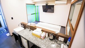 Un baño de hotel con un lavamanos grande, un espejo y un televisor montado en la pared.