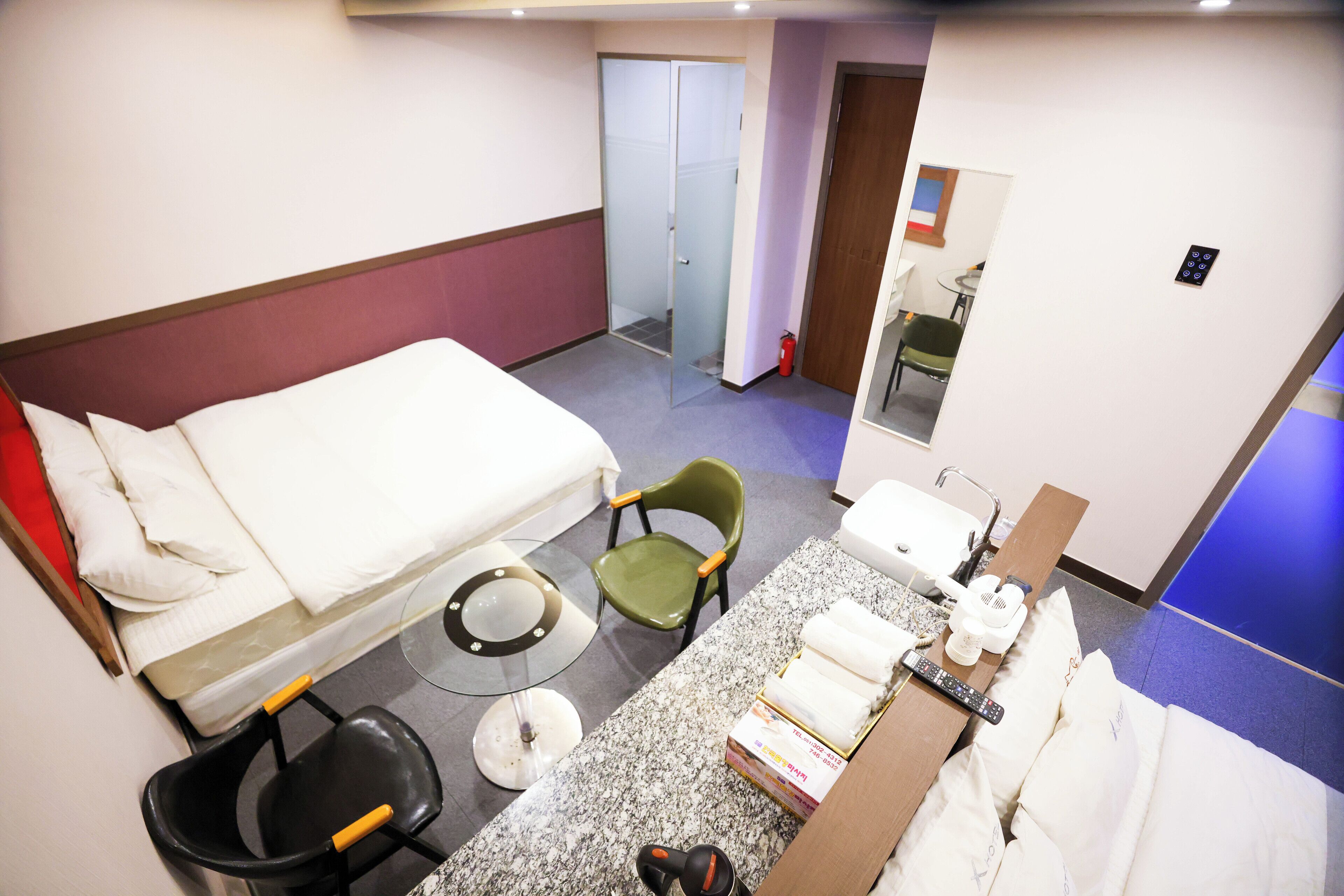 Ett hotellrum med en säng, ett litet bord, en stol, en toalett och en spegel.