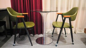 Una habitación con una mesa redonda de vidrio y dos sillas verdes con detalles naranja.
