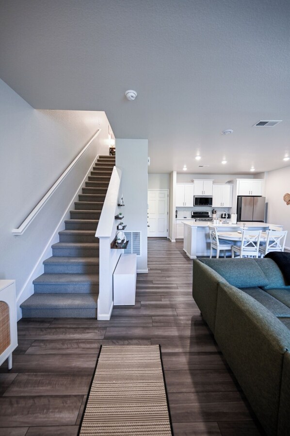 A modern kitchen with white cabinets, a central island, and a dining area with white chairs.