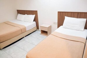 A hotel room with two single beds, each with a wooden headboard, white bedding, and a beige blanket. There is a small bedside table between the beds. - Impress Star Hotel (Senai)