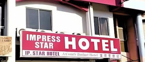 A hotel sign with the name 'IMPRESS STAR HOTEL' and a partial view of the building facade.