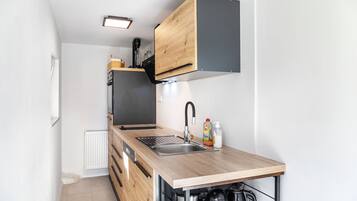 A compact kitchen with a wooden countertop, a built-in sink, and a black range hood.