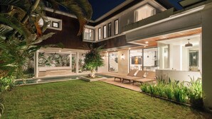 A modern house with a pool, outdoor seating, and lush greenery. - Melasti Villa 2 by Alfred in Bali (Canggu)