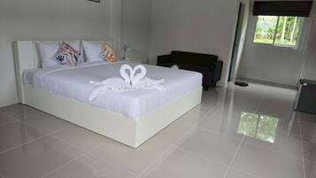 A modern hotel room with a large bed, white bedding, and a heart-shaped towel decoration.