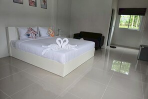 Une chambre d’hôtel moderne avec un grand lit, du linge de lit blanc et une décoration en forme de cœur faite avec une serviette.